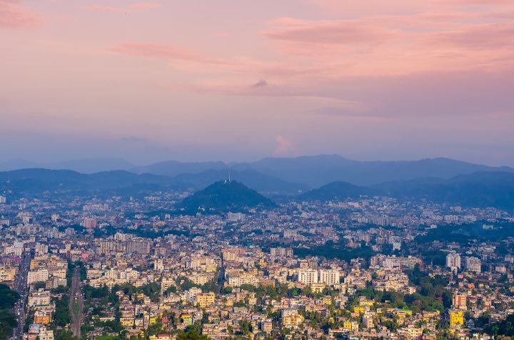 Guwahati city spread below Nilachal hill at dusk, with hills on the horizon