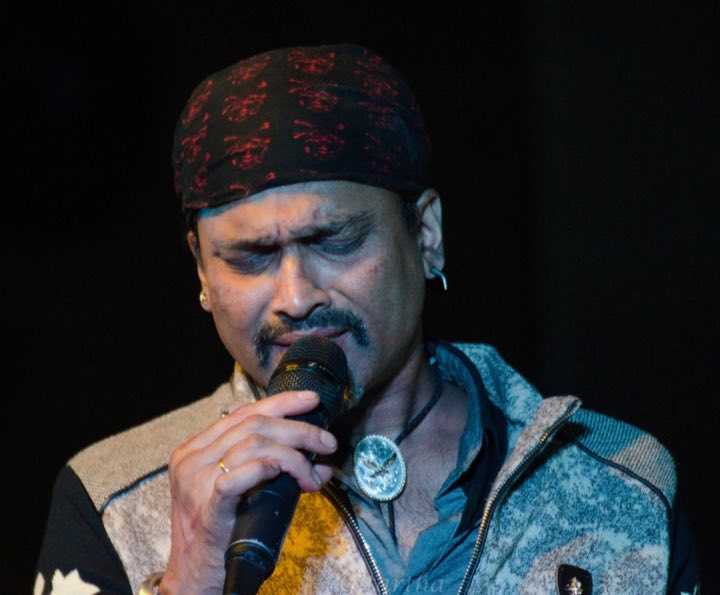 Zubeen Garg singing into a microphone on stage, eyes closed
